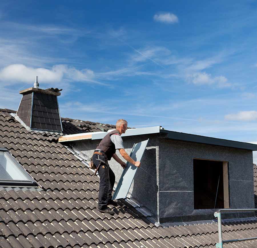 Mann auf einem Dach mit Werkzeug und Material für eine Montage